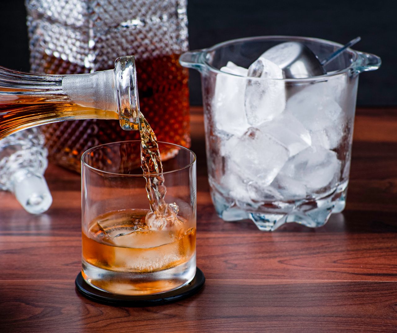 A close-up of whiskey being poured into a glass with ice, perfect for cocktail imagery.